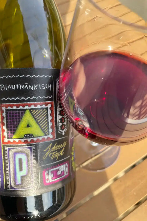 Bottle and glass of Johannes Trapl Blaufraenkisch 2023 - Natural Wine Dealers