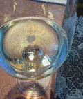 A clear wine glass with a sparkling wine viewed from above on a brown surface, with a dark wine bottle.